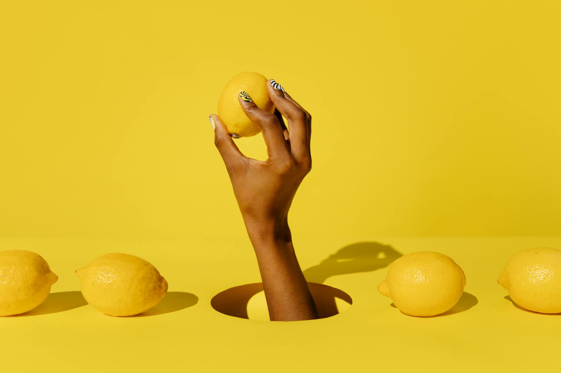 A hand holding a lemon against a vivid yellow background, symbolizing fresh self-discovery