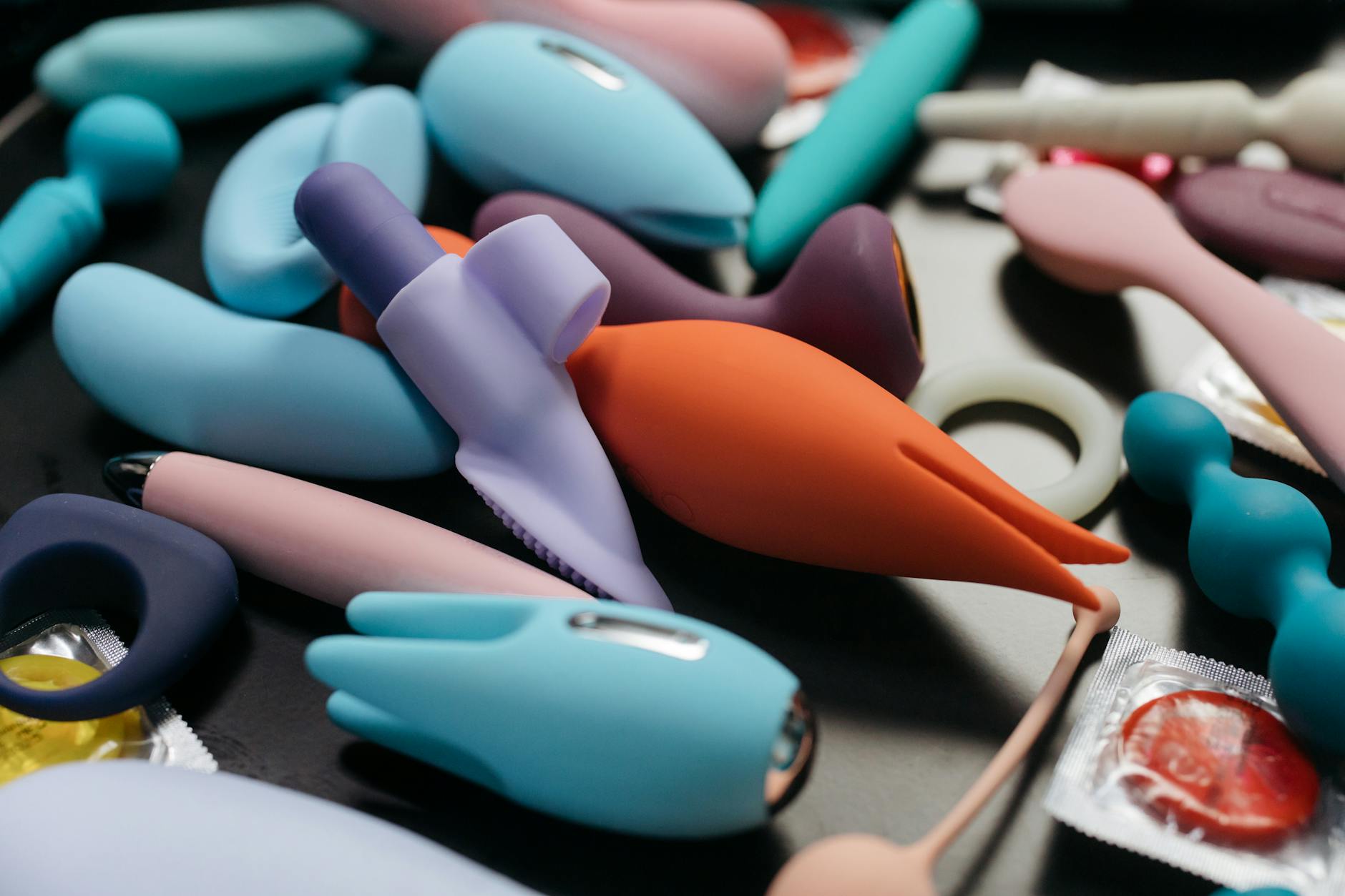 Woman in glasses contemplating different colored clitoral vibrators