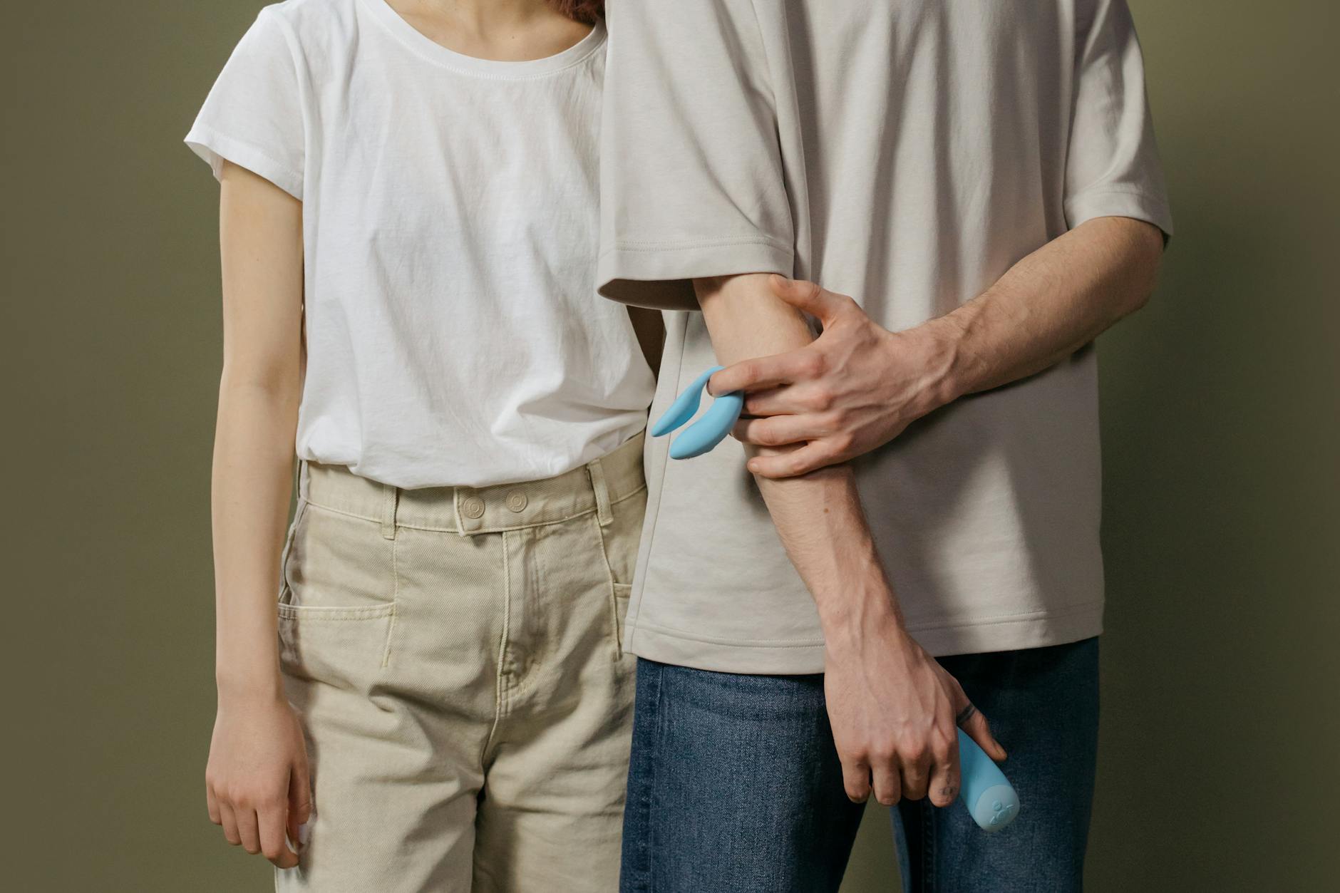 A young couple holding a vibrator together, representing modern intimacy and shared discovery